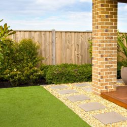 jardin avec terrasse en bois, pilier en briques et gazon synthétique réaliste