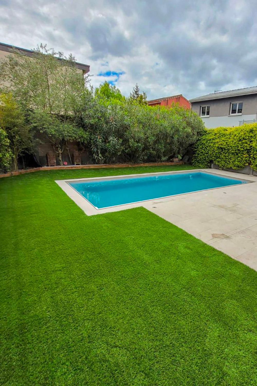 Pourquoi choisir le gazon synthétique en 2025 ? 34 Gazon synthétique atour d'une piscine dans un jardin